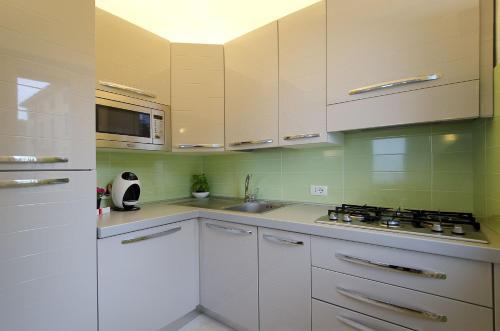 a kitchen with white cabinets and a sink and a stove at Appartamento a 5 metri dal lago in Torri del Benaco