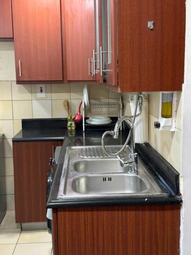 a kitchen with a stainless steel sink and wooden cabinets at JBR Skyview Rooms in Dubai