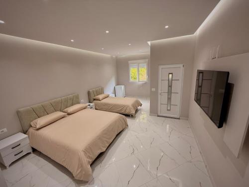 a bedroom with two beds and a flat screen tv at Selami GuestHouse in Peshkopi