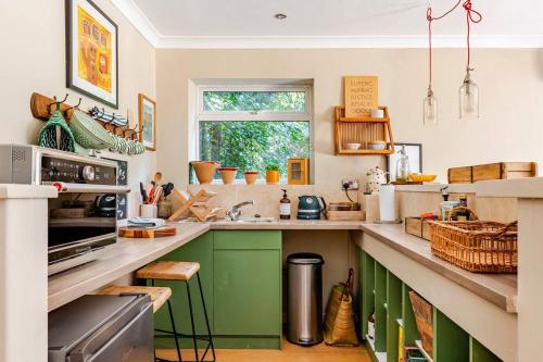 a kitchen with green cabinets and a window at The Old Pool House, Stylish Large Studio in Private Country Estate with Air Con in Bradford on Avon