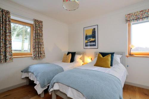 una camera da letto con due letti e una finestra di Beautiful Lodge with hot tub & panoramic views a Boat of Garten