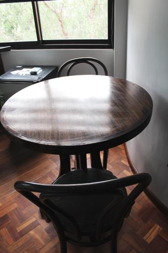 a wooden table with a black chair in front of a window at Kunan Hotel in Cochabamba