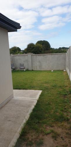 a backyard with a concrete fence and a grass yard at Electric Picnic Accommodation in Stradbally