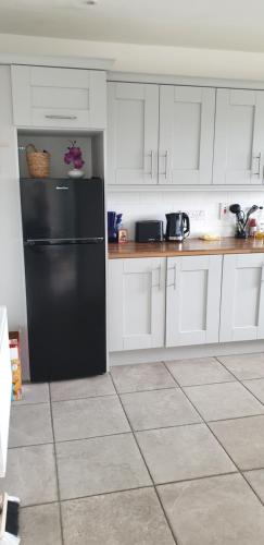 a kitchen with a black refrigerator and white cabinets at Electric Picnic Accommodation in Stradbally