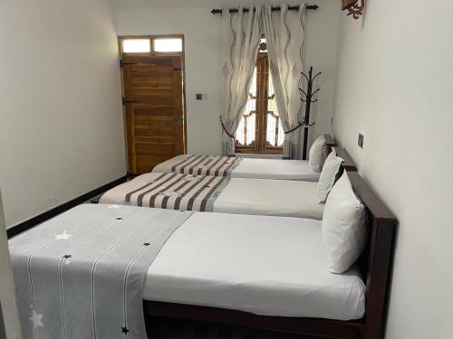 two beds in a room with a window at Sea View Resort in Kallady