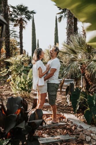 a man and a woman standing in front of palm trees at Tropicana Lodge - Sardaigne in Roquebrune-sur-Argens