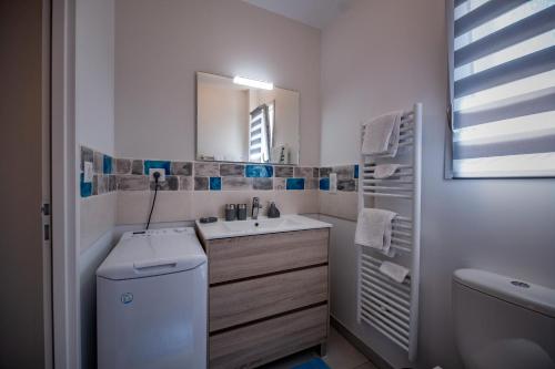ein weißes Badezimmer mit Waschbecken und Toilette in der Unterkunft Le Rayon de Soleil in Saint-Georges-de-Didonne