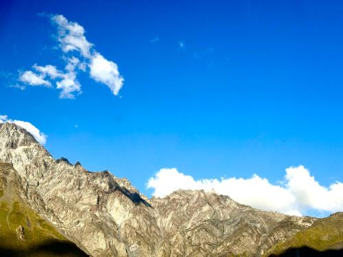 a mountain range with a blue sky and clouds at Hotel Daba Kazbegi in Stepantsminda