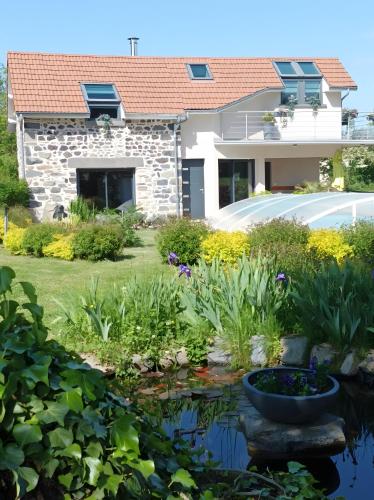 a garden with a pond in front of a house at Gite Des Taravelles in Manzat