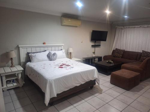 a bedroom with a large bed and a couch at Bella Cottage Escape in Rooihuiskraal