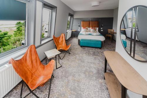 a bedroom with a bed and two chairs and a mirror at The Hebridean - Rooms & Apartments in Broadford