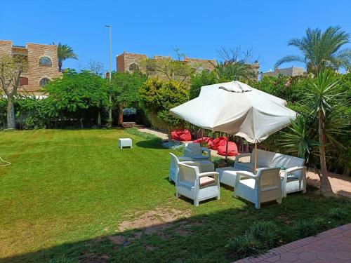 a group of chairs and an umbrella in a yard at مارينا الساحل الشمالى in El Alamein
