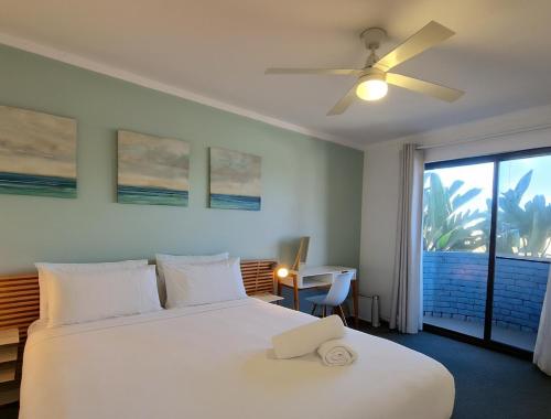 a bedroom with a white bed with a ceiling fan at Coastal Scarborough Beach Chic Pool View 2BR in Perth