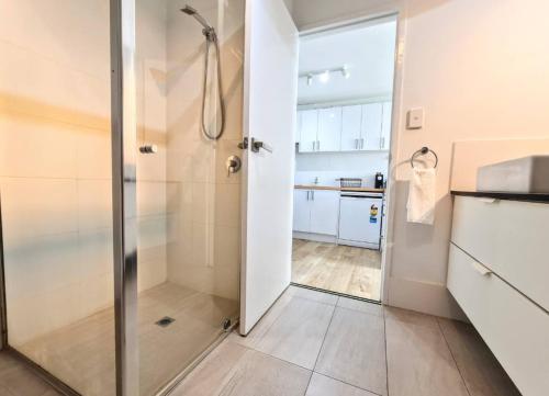 a bathroom with a shower with a glass door at Coastal Scarborough Beach Chic Pool View 2BR in Perth