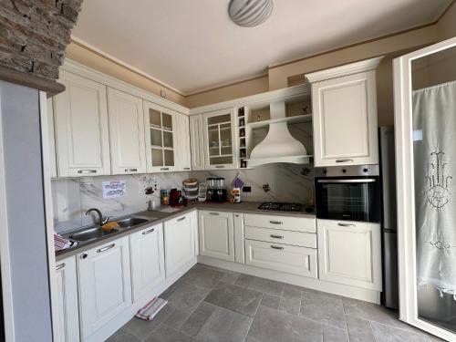a kitchen with white cabinets and a sink at Casa in mezzo agli Ulivi in Lamporecchio