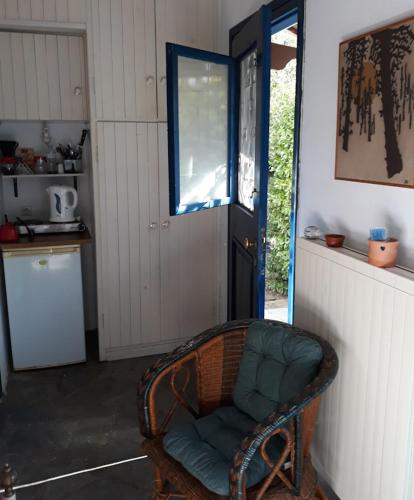 a room with a chair in a kitchen with a door at Kleines gemütliches Studio mit Terrasse, im Grünen gelegen in Agios Ioannis