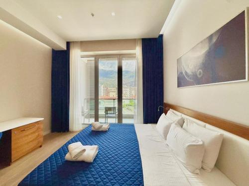 a bedroom with a blue bed with a large window at Condo Studio Plaza in Budva
