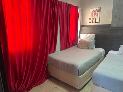 Una habitación con cortinas rojas y una cama y una cama cuadrada. en Latona Guest House, en Johannesburgo