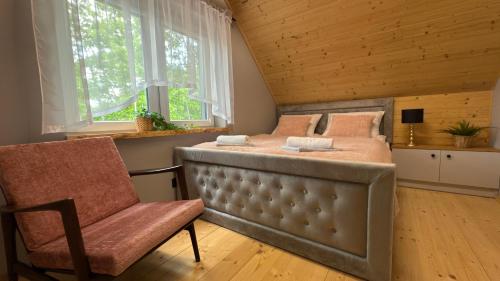 a bedroom with a bed and a chair and windows at "Źródło zasilania" domki letniskowe nad Zalewem Chańcza in Raków