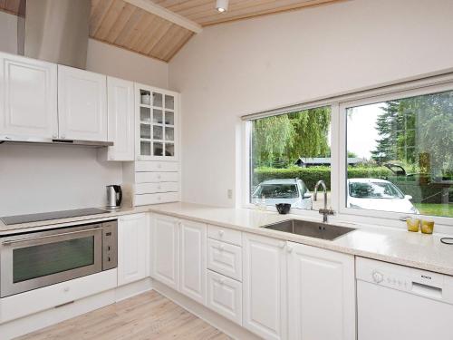 a white kitchen with a sink and a window at 10 person holiday home in Juelsminde-By Traum in Juelsminde