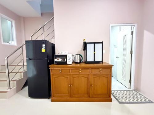 La cuisine est équipée d'un réfrigérateur noir et d'une armoire en bois. dans l'établissement House Near Hatyai City, 5-7pax, Free2Parking&Wi-Fi, à Hat Yai