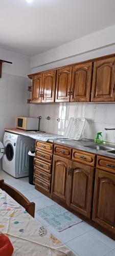 a kitchen with wooden cabinets and a microwave at As Chaves do Cantinho da Paz in Santarém