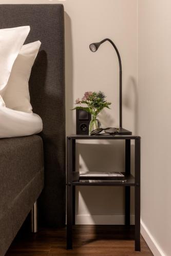 a nightstand with a lamp and a plant on it next to a bed at Bob W Stockholm Gamla Stan in Stockholm