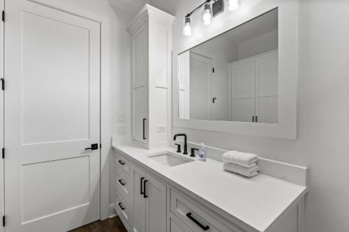 a white bathroom with a sink and a mirror at Salty Seabass 4BR Seaside Escape in Port Bolivar