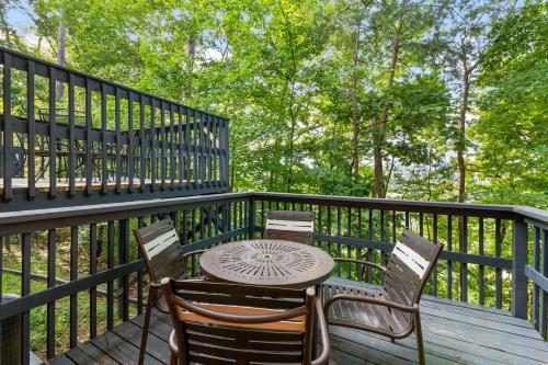 a table and chairs on a deck with trees at Relaxing Escape Pool Access & Close to Dollywood in Pigeon Forge
