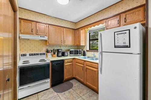 a kitchen with wooden cabinets and a white refrigerator at Cozy Retreat awaits w Pool Grill Near Dollywood in Pigeon Forge