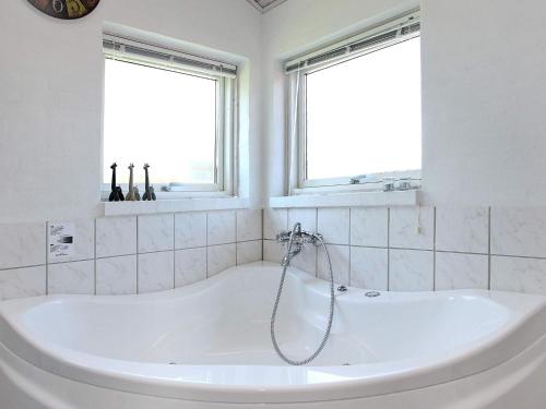 a white bath tub in a bathroom with two windows at 4 star holiday home in Hjørring in Lønstrup