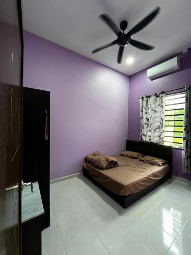 Un dormitorio con ventilador de techo y paredes moradas. en AZZR Homestay, en Kuala Terengganu