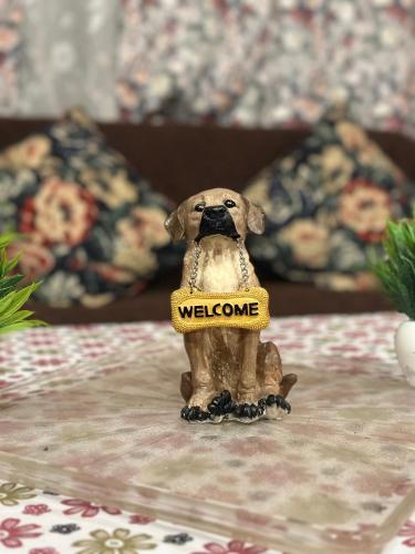 a small figurine of a dog wearing a welcome sign at LA Address Retreat - The Heritage Homestay in Ooty