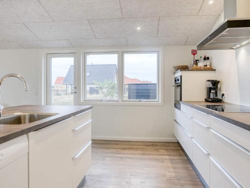 a kitchen with white cabinets and a sink and two windows at 6 person holiday home in Læsø-By Traum in Læsø