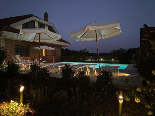 a swimming pool with two white umbrellas and a pool at Villa Martini dei Rossi in Sanfrè