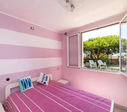 1 dormitorio con cama morada y ventana en La Casetta rosa, en Diano Marina