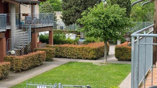 a garden with a tree and bushes and a building at ENJOY HOUSE in Ronchi