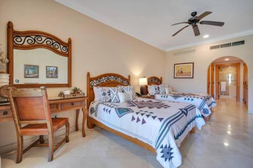 Un dormitorio con dos camas y un escritorio y un ventilador de techo. en Beachfront Premium Ocean View 5 Star Beach View, en Cabo San Lucas