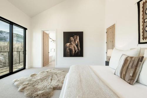 a white bedroom with a large bed and a large window at White Pine Luxe Family Retreat with Views in Snyderville
