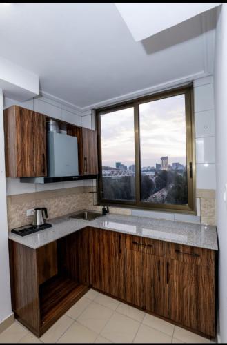 a kitchen with wooden cabinets and a large window at Queen Hotel in Addis Ababa