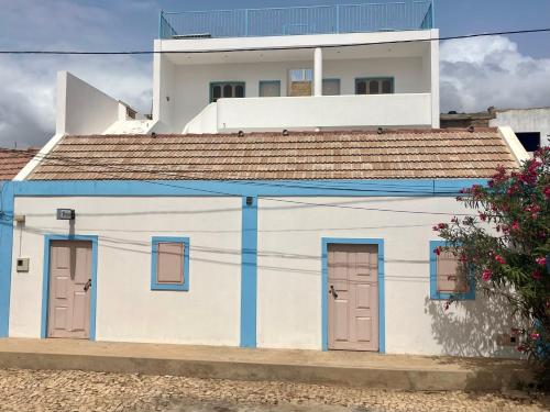a white building with blue doors and a house at Onda Kriola in Vila do Maio