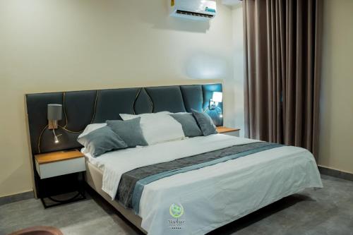 a bedroom with a large bed with a black headboard at Maghaz Royal Hotel in Tamale