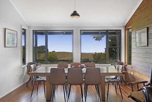 a dining room with a table and chairs and windows at Anderlaine at Wootha in Booroobin