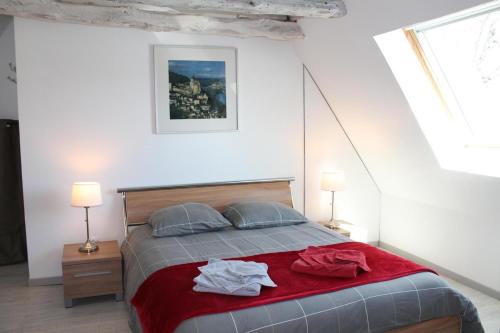 una camera da letto con un letto con lenzuola rosse e due lampade di Les Mazaux avec piscine chauffée au nord de Sarlat a La Chapelle-Aubareil