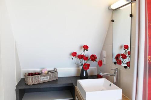 un bagno con lavandino e vaso con fiori rossi di Les Mazaux avec piscine chauffée au nord de Sarlat a La Chapelle-Aubareil