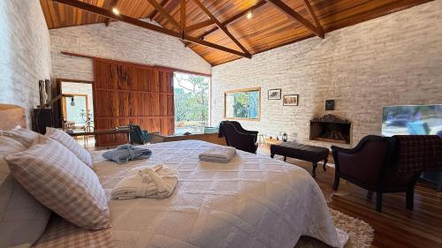 a bedroom with a large bed and a fireplace at Espetacular casa em Gonçalves - MG (2) in Gonçalves