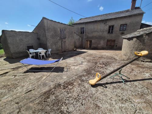 an outdoor area with a table and a swing at Maison spacieuse 8 couchages proche cascade lac et base de loisirs et de bien être in Lacaze