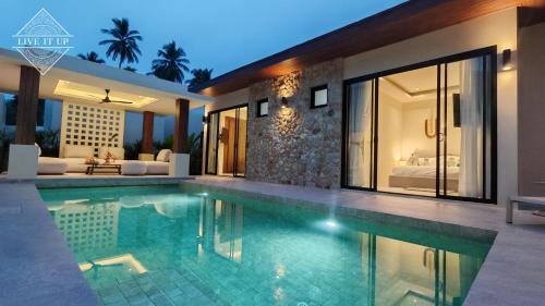 a swimming pool in front of a villa at Santi Tara Villas in Amphoe Koh Samui