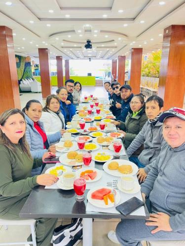 にあるHostería Don Polyの長いテーブルに座って食べ物を食べる人々