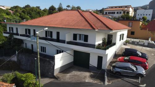 a white house with two cars parked in a parking lot at Sea and Sun 4 You - Villa Jardim in Santana